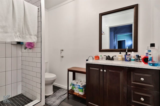 bathroom with tiled shower, vanity, and toilet