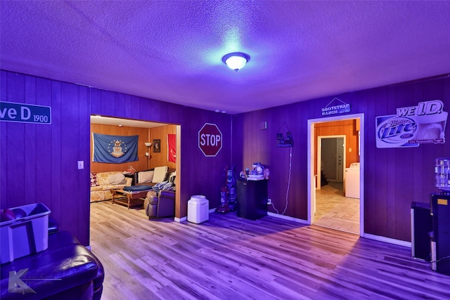 interior space featuring washer / clothes dryer, a textured ceiling, wood walls, and hardwood / wood-style floors