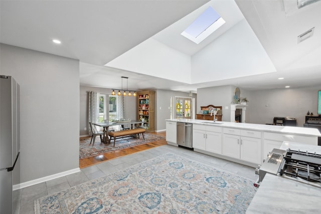 kitchen with stainless steel appliances, sink, an inviting chandelier, light hardwood / wood-style floors, and white cabinetry