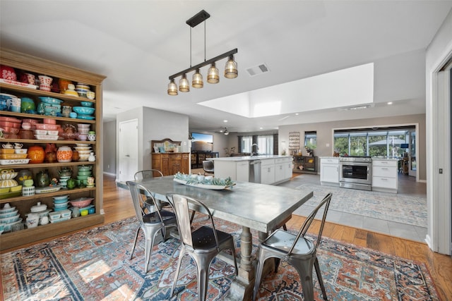 dining space featuring a skylight, ceiling fan, and light hardwood / wood-style floors