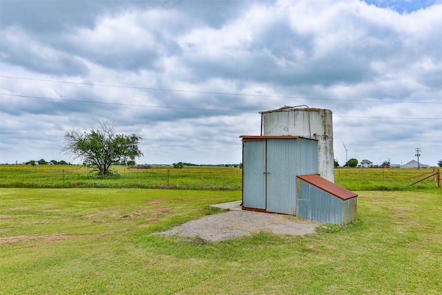 view of outbuilding with a rural view and a yard