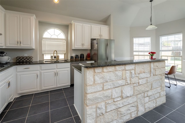 kitchen with white cabinetry, appliances with stainless steel finishes, a center island, sink, and dark tile patterned floors