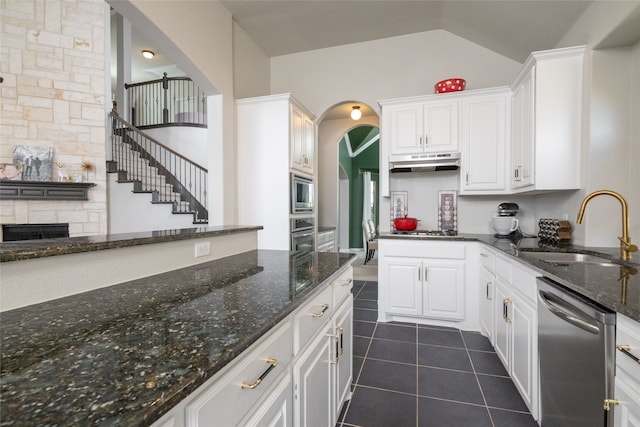 kitchen featuring appliances with stainless steel finishes, white cabinets, dark stone counters, and sink