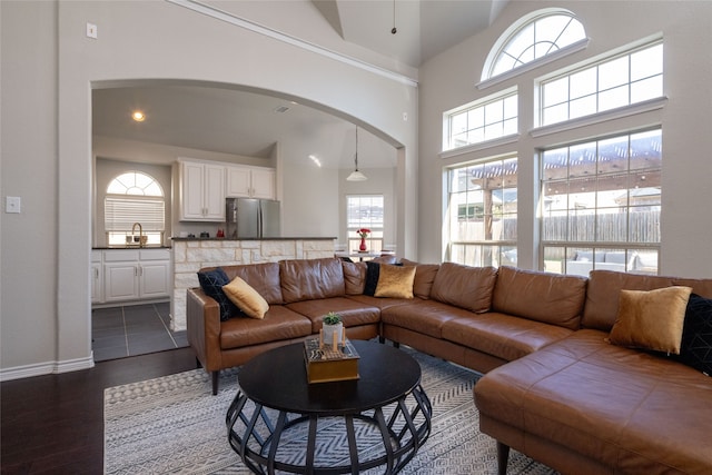 living room with sink, dark hardwood / wood-style floors, and a towering ceiling