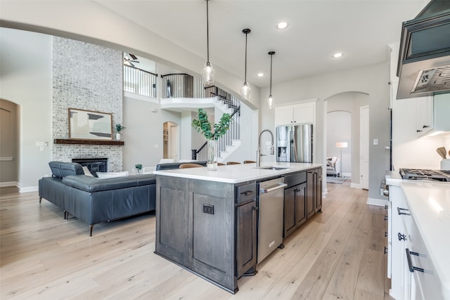 kitchen featuring a stone fireplace, white cabinetry, light wood-type flooring, and stainless steel appliances