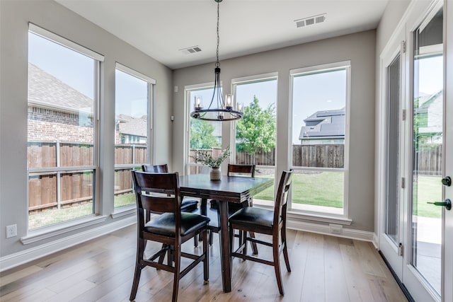 dining space featuring light hardwood / wood-style floors, an inviting chandelier, and plenty of natural light