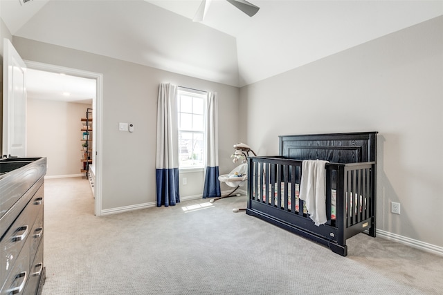 carpeted bedroom featuring ceiling fan, vaulted ceiling, and a nursery area