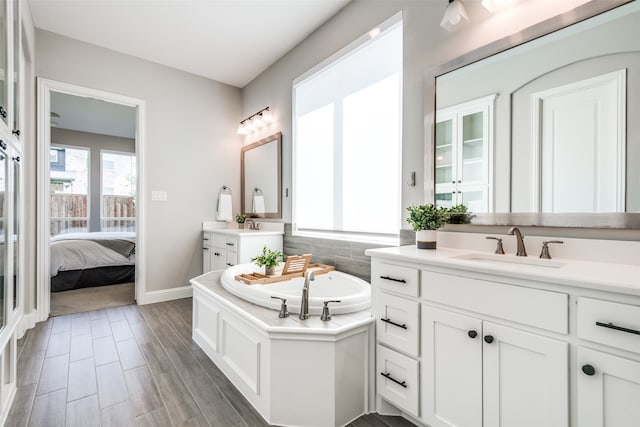 bathroom with hardwood / wood-style flooring, vanity, and a tub to relax in