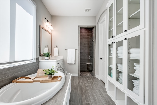 bathroom with hardwood / wood-style floors, vanity, separate shower and tub, and tile walls