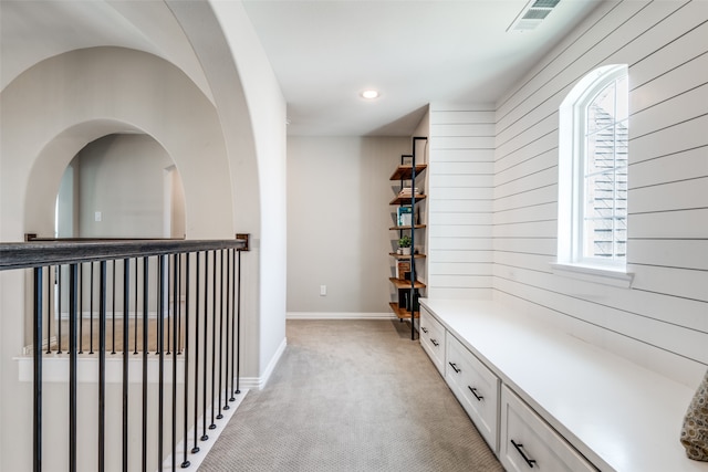 hallway featuring wood walls and light colored carpet