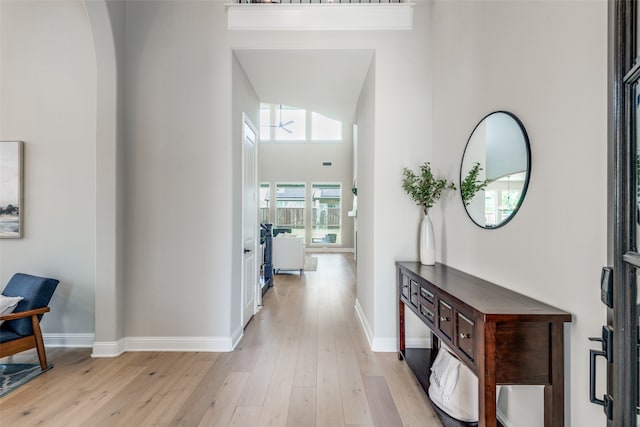 corridor featuring a towering ceiling and light hardwood / wood-style flooring