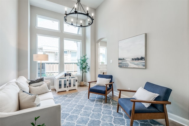 sitting room featuring a towering ceiling, hardwood / wood-style flooring, and a notable chandelier