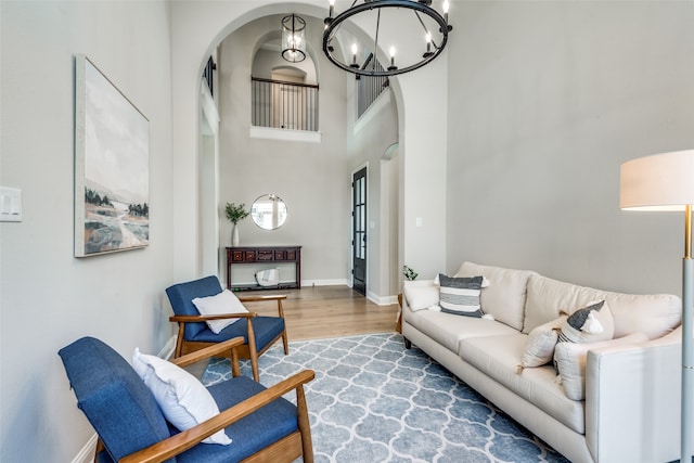 living room with a towering ceiling, a notable chandelier, and light wood-type flooring