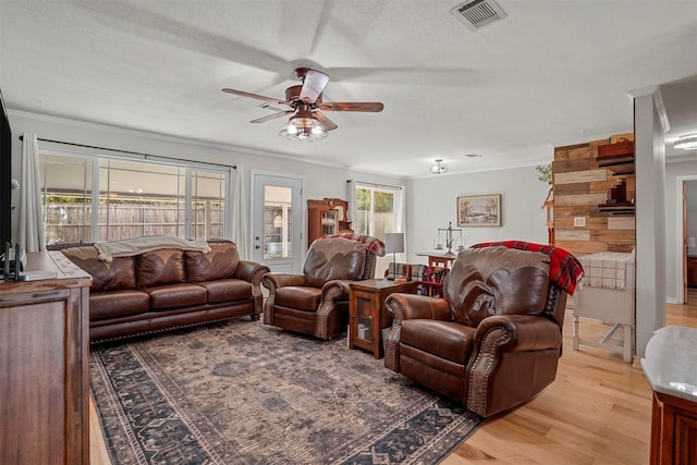 living room featuring a textured ceiling, light wood-type flooring, ceiling fan, and ornamental molding