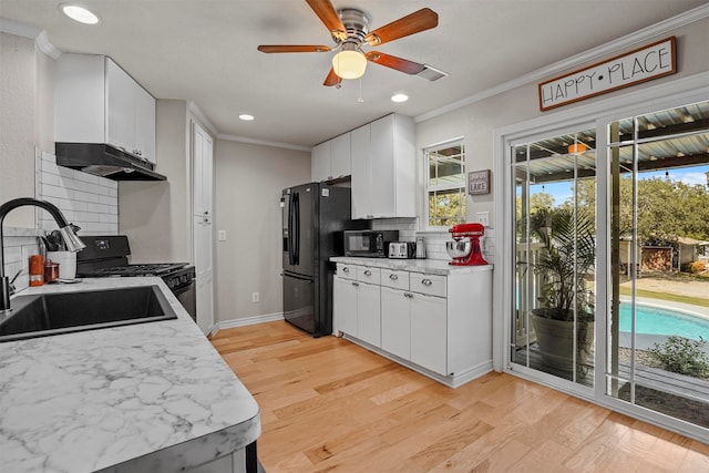 kitchen with decorative backsplash, white cabinetry, and black appliances