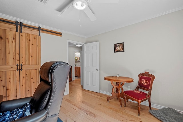 home office featuring a barn door, crown molding, ceiling fan, and light wood-type flooring