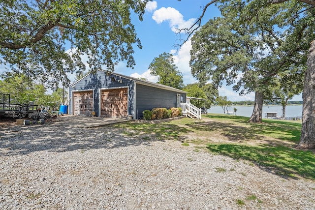 exterior space featuring a garage, an outdoor structure, and a water view