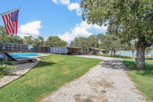 view of yard featuring a storage unit, a water view, and a fenced in pool