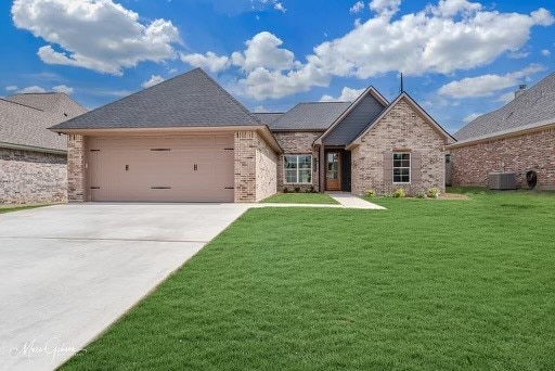 view of front facade with cooling unit, a garage, and a front lawn