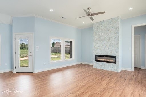 unfurnished living room with crown molding, a fireplace, ceiling fan, and light hardwood / wood-style flooring