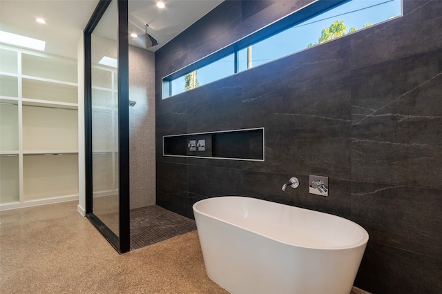 bathroom featuring tile walls and independent shower and bath