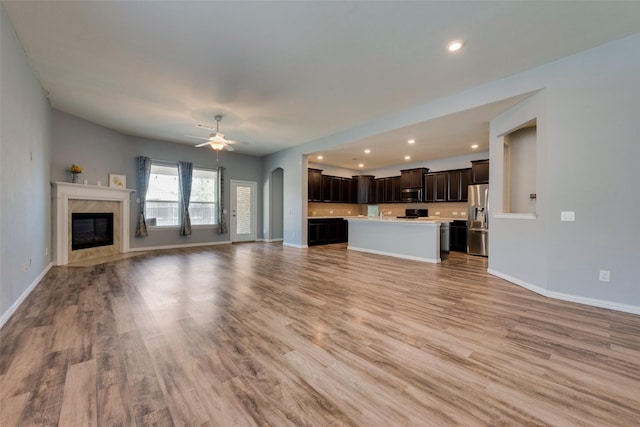 unfurnished living room featuring light hardwood / wood-style floors, ceiling fan, and a premium fireplace