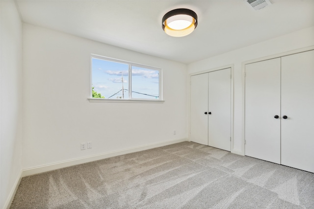 unfurnished bedroom with light carpet and two closets