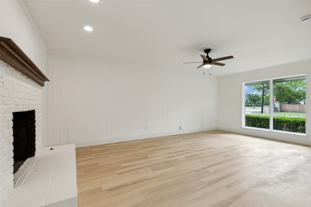 unfurnished living room featuring light hardwood / wood-style floors, a fireplace, ornamental molding, and ceiling fan