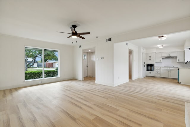 unfurnished living room featuring light hardwood / wood-style flooring, ceiling fan, and sink