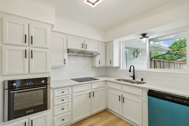 kitchen with decorative backsplash, light hardwood / wood-style floors, white cabinetry, black appliances, and sink