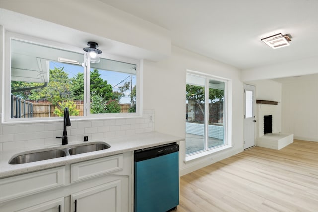 kitchen featuring dishwasher, sink, white cabinetry, and a wealth of natural light