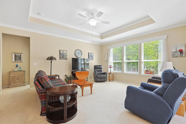 living room with crown molding, a tray ceiling, ceiling fan, and light colored carpet