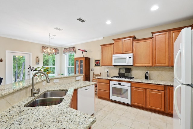 kitchen with light stone counters, decorative light fixtures, sink, and white appliances