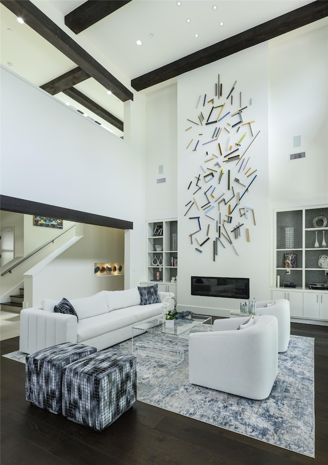 living room with dark wood-type flooring, a towering ceiling, and beamed ceiling