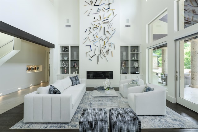 living room with dark hardwood / wood-style floors, built in features, and a towering ceiling