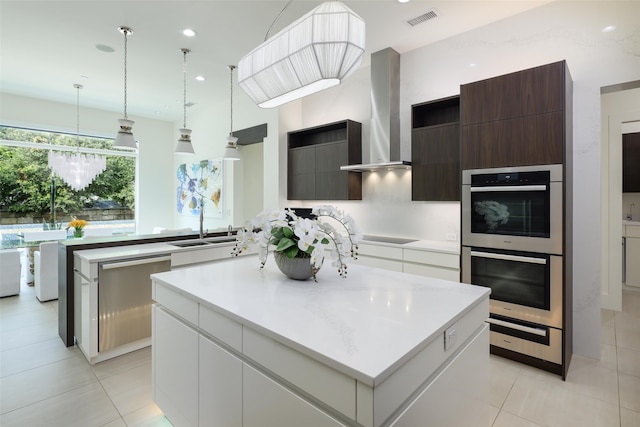 kitchen with stainless steel appliances, dark brown cabinets, wall chimney exhaust hood, white cabinets, and a center island