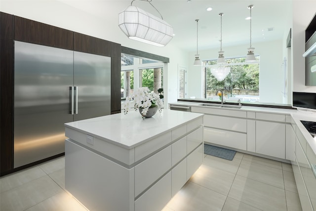 kitchen featuring stainless steel appliances, dark brown cabinets, a kitchen island, white cabinets, and sink