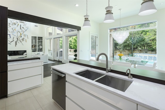 kitchen with white cabinetry, stainless steel dishwasher, and hanging light fixtures