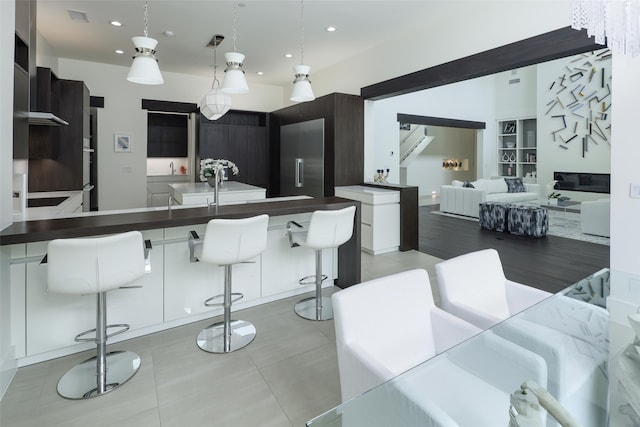 kitchen featuring a breakfast bar area, white cabinetry, hanging light fixtures, and high end fridge