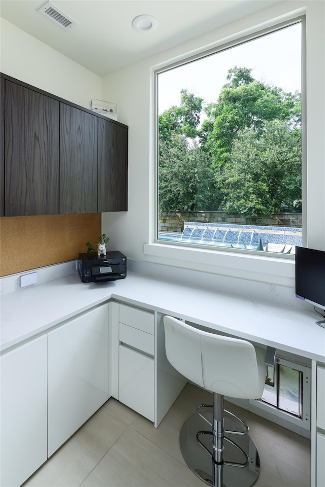 unfurnished office featuring built in desk and light tile patterned floors