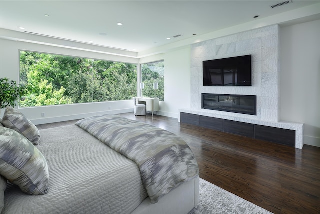 bedroom with dark hardwood / wood-style floors and a tile fireplace