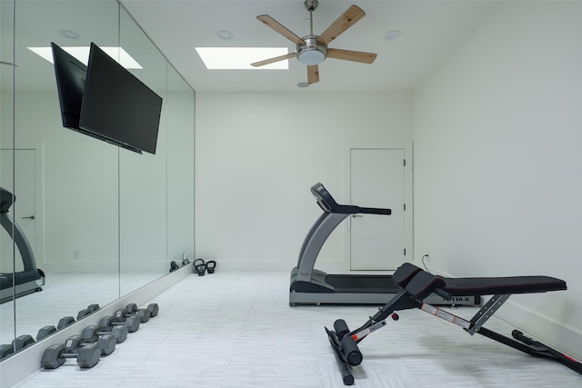 workout room with ceiling fan and a skylight