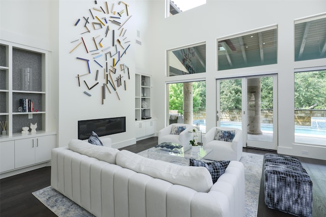 living room with a high ceiling, built in features, and dark hardwood / wood-style floors