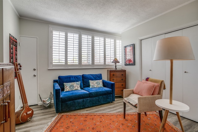 sitting room featuring a textured ceiling, light wood-type flooring, and crown molding