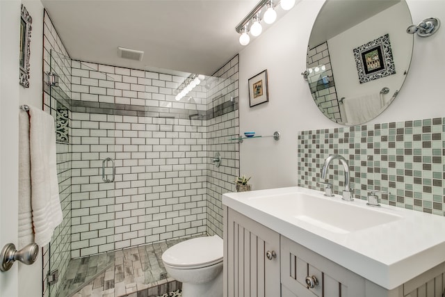 bathroom with tile walls, a shower with door, vanity, and toilet