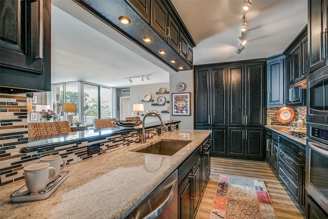 kitchen with light hardwood / wood-style floors, tasteful backsplash, sink, appliances with stainless steel finishes, and light stone countertops