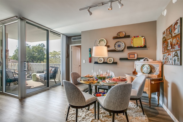 dining space with wood-type flooring, floor to ceiling windows, and track lighting