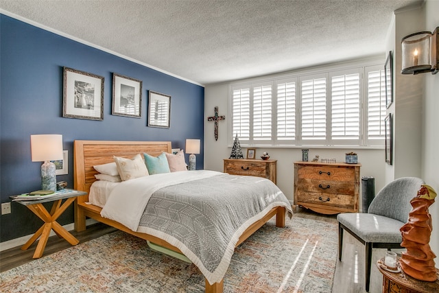 bedroom with a textured ceiling, crown molding, and hardwood / wood-style floors