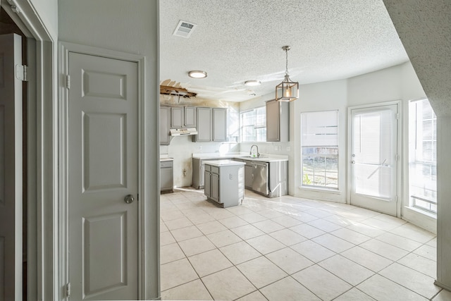 kitchen featuring light tile patterned flooring, a center island, dishwasher, and decorative light fixtures