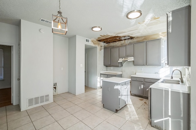 kitchen with a kitchen island, sink, light tile patterned flooring, pendant lighting, and a textured ceiling